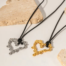 Load image into Gallery viewer, This glam rock necklace is made of gold plated stainless steel pendant which is hanging on a black wax rope. The hollow heart pendant comes in two colours: gold and silver. Its shape imitates lava, which gives the necklace an interesting look. It is a perfect piece for any daily occasion. 
