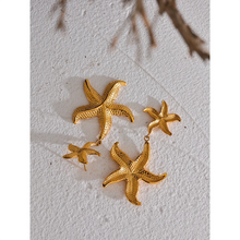 Load image into Gallery viewer, Elevate your summer style with our gold-plated stainless steel starfish dangle earrings, designed for women who love bold and beachy accessories. These high-quality earrings feature an eye-catching drop design with two charming starfish—one smaller and one larger—hanging gracefully below each other for added dimension and movement.
