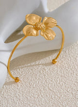 Load image into Gallery viewer, Embrace bold elegance with this stunning charm metal flower cuff bracelet, a statement piece designed to captivate. Featuring an intricate large flower motif, this open bangle is crafted from high-quality stainless steel and plated in radiant 18K gold for a luxurious finish. Its sleek, thin band beautifully contrasts with the striking floral design, creating a unique balance of sophistication and flair.
