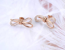 Load image into Gallery viewer, Charming stainless steel earrings are made in a rose gold colour. Earrings are made in a shape of a bow which is adorned with beautiful cubic zirconia. Earrings are rose gold plated and represent elegant and classy accessory for your smart outfit. They have stud fastening.
