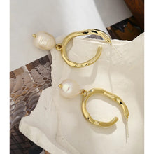 Load image into Gallery viewer, Elegant metal earrings are made in a gold colour. They consists of a big irregular hoop on which a natural pearl is attached. Earrings has real gold plating and represent perfect and elegant touch to your classy and elegant outfit. They have stud fastening.
