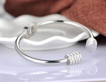 Load image into Gallery viewer, Elegant and luxurious bangle bracelet is made of stainless steel. It comes in two colours: rose gold and silver. It is adorned with rollers on each of its ends. Rollers have lines of embedded cubic zirconia in silver colour. It is a perfect bracelet for glamorous evening. 
