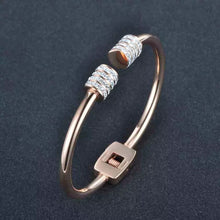 Load image into Gallery viewer, Elegant and luxurious bangle bracelet is made of stainless steel. It comes in two colours: rose gold and silver. It is adorned with rollers on each of its ends. Rollers have lines of embedded cubic zirconia in silver colour. It is a perfect bracelet for glamorous evening. 
