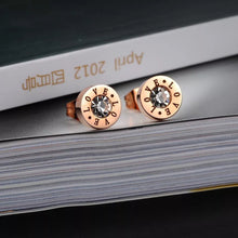 Load image into Gallery viewer, Little round earrings are made of stainless steel in a rose gold colour. They are adorned with cubic zirconia in the middle and engraved &quot;LOVE&quot; letters around it. Earrings are rose gold plated and represent perfect and elegant touch to your day to day style. They have stud fastening.
