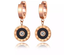 Load image into Gallery viewer, Classic earrings, made of stainless steel, are coming in rose gold colour. Their surface is three times gold plated. These small and elegant earrings are adorned with a circle adorned with black smaller circle, roman numerals and cubic zirconia in the middle. Earrings are wearable for any occasion and have French closure.
