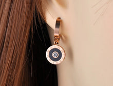 Load image into Gallery viewer, Classic earrings, made of stainless steel, are coming in rose gold colour. Their surface is three times gold plated. These small and elegant earrings are adorned with a circle adorned with black smaller circle, roman numerals and cubic zirconia in the middle. Earrings are wearable for any occasion and have French closure.
