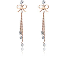 Load image into Gallery viewer, These beautiful bohemian earrings are made of stainless steel which is three times gold plated.  They come in a rose gold colour. They have one bigger cubic zirconia under which cute little bowknot is situated. Three delicate chains are hanging from the bowknot and each ends with a small transparent cubic zirconia. Earrings makes perfect accessory for your evening outfit. They have stud closure.
