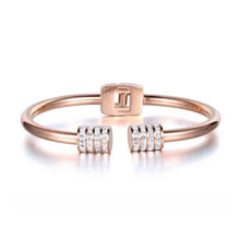 Load image into Gallery viewer, Elegant and luxurious bangle bracelet is made of stainless steel. It comes in two colours: rose gold and silver. It is adorned with rollers on each of its ends. Rollers have lines of embedded cubic zirconia in silver colour. It is a perfect bracelet for glamorous evening. 
