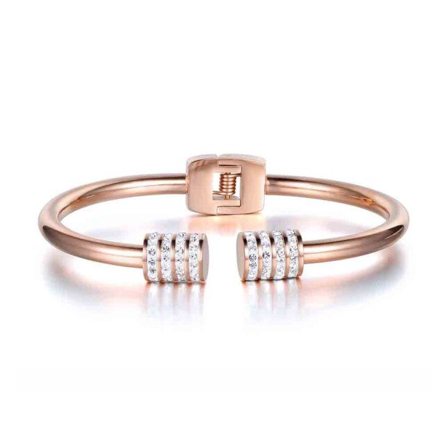 Elegant and luxurious bangle bracelet is made of stainless steel. It comes in two colours: rose gold and silver. It is adorned with rollers on each of its ends. Rollers have lines of embedded cubic zirconia in silver colour. It is a perfect bracelet for glamorous evening. 