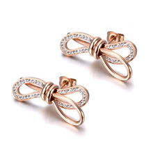 Load image into Gallery viewer, Charming stainless steel earrings are made in a rose gold colour. Earrings are made in a shape of a bow which is adorned with beautiful cubic zirconia. Earrings are rose gold plated and represent elegant and classy accessory for your smart outfit. They have stud fastening.
