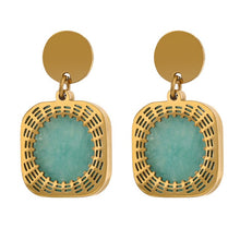 Load image into Gallery viewer, Elegant stainless steel earrings are made in a gold colour. They consists of a small circle on which turquoise natural stone is hanging. The natural stone is circled with gold and carved stainless steel rim. Earrings have real gold plating and represent great accessory to your elegant outfit. They have stud fastening.
