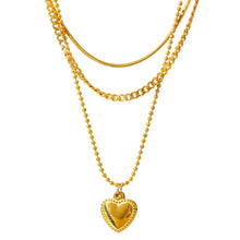 Load image into Gallery viewer, Stainless steel necklace comes in a gold colour and it is three times gold plated. This layered necklace is made of three different chains. The longest one is adorned with a little pedant in a shape of a heart. The heart is decorated with small engraved circles around its border. The chain necklace is perfect for any outfit. It has adjustable length and lobster clasp.
